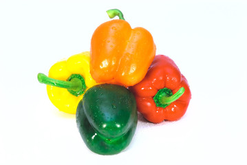 four colorful peppers over white