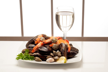 piatto con cozze  gamberi e vongole e vino bianco