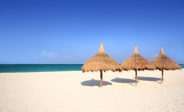 Grass umbrellas on a white sand beach