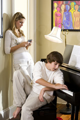Teenager brother and sister at home by piano