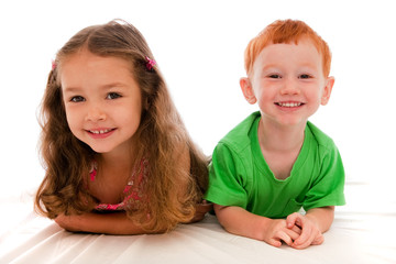 Young girl and boy lying together on bed