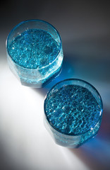 two glass with blue liquid and bubbles of oil