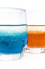 two glass with red and blue liquid and bubbles of oil