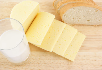 Cheese, bread and glass of milk on wooden background