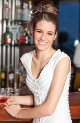 Young woman with hairstyle at bar drinking and smiling