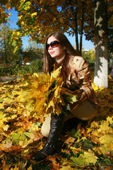 The woman squats with an armful of maple leaves