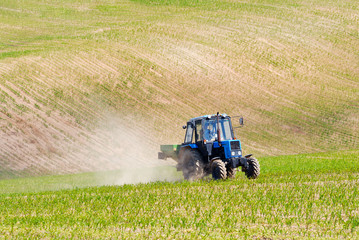 Fototapeta premium Tractor in a field in early summer