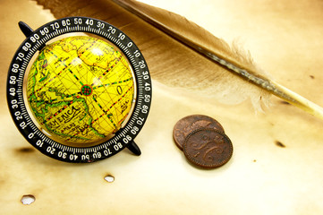 Fototapeta na wymiar Antique globe, feather and old coins