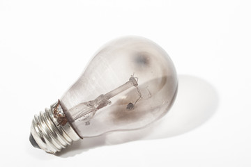 Burnt out light bulb against white background with shadow