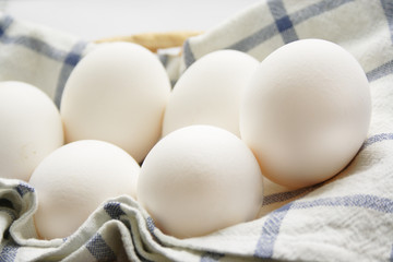 Eggs on white and blue towel in the wood basket