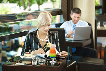 Woman reading magazine in cafe