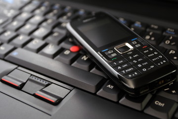 Obraz premium Mobile phone and laptop keyboard