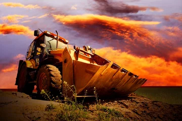 Foto op Plexiglas Yellow tractor on golden surise sky © Andrii IURLOV