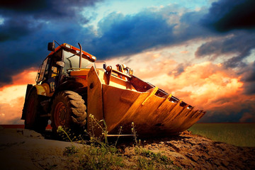 Yellow tractor on golden surise sky