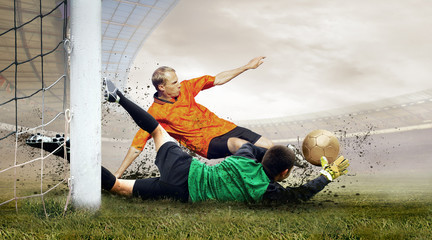 Shoot of football player and jump of goalkeeper on the field of