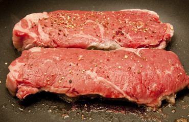 Two Steaks Sizzling in a Pan