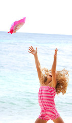 happy girl throwing her hat up on sea background