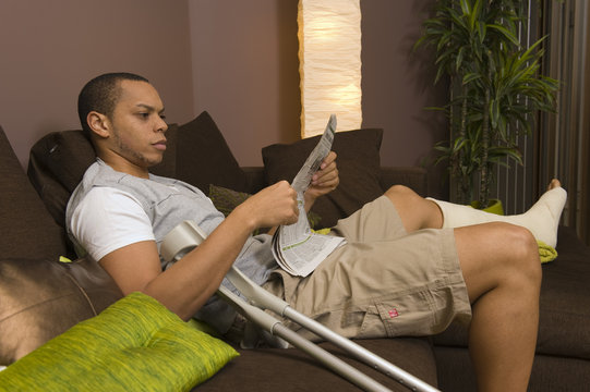 Homme plâtré lisant un journal dans son salon