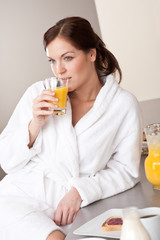 Young woman enjoying orange juice  in kitchen