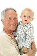 Studio Portrait Of Grandfather Holding Grandson