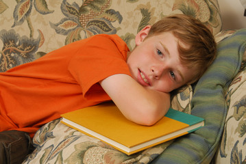 Boy with a school book resting