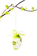 Easter egg on a branch with leaves on white isolated background