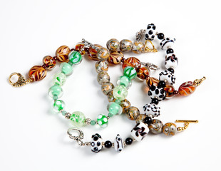 A selection of hand made bracelets and earrings against white
