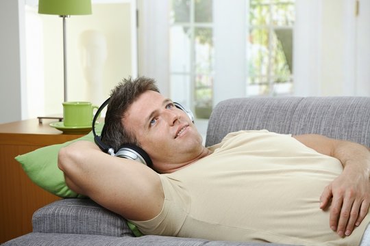 Man on sofa listening to music smiling