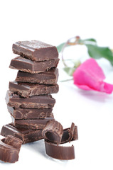 Chocolate, table, pieces and rose on white background