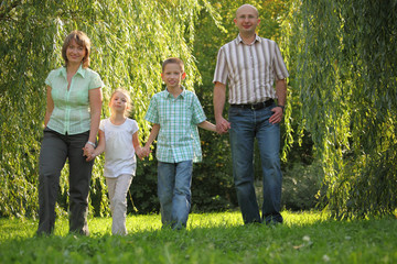 dad, mom, son and daughter is walking in early fall park.