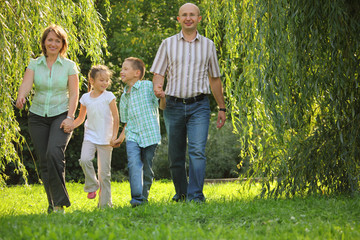 smiling family with two children is walking in early fall park.