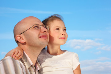 Fototapeta premium father and little girl on sky background are looking at sky