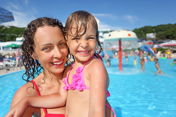 Fototapeta na wymiar Smiling beautiful woman and little girl bathing in pool