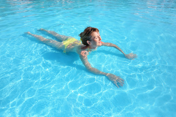 Fototapeta na wymiar young beautiful woman swimming in yellow bikini in paddling pool