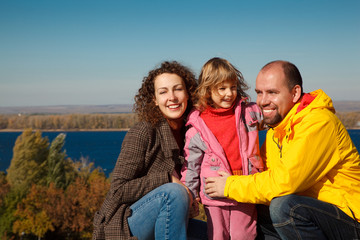 Little girl with mum and daddy, in bright autumn day