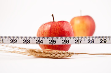 Two red Apples, one in focus behind a tape measure