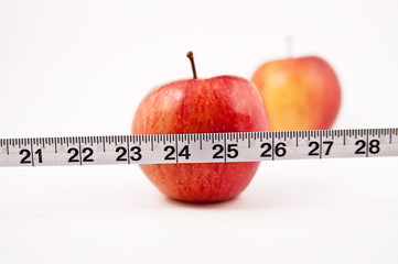 Two red Apples, one in focus behind a tape measure
