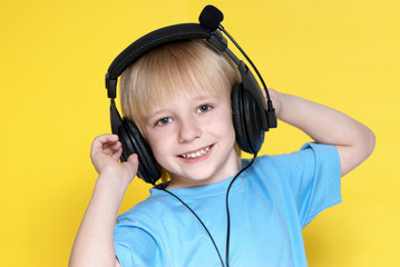 The emotional kid in ear-phones on a yellow background