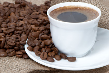 Coffee cup close-up over dark roasted coffee beans
