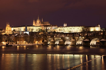 Fototapeta na wymiar Snowy Pradze gotyckiego zamku z mostu Karola w nocy