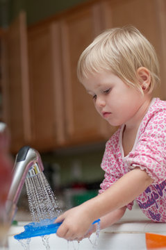 3 years old girl washing the dishes