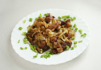 fried cabbage with fried pork meat on a white plate