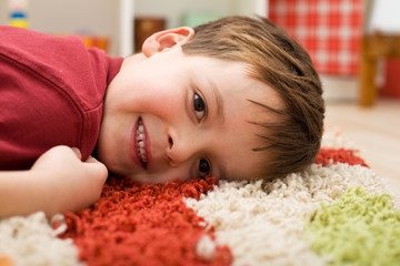 Obraz na płótnie Canvas Happy boy laying on a rug