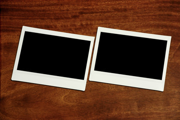 two empty polaroids on wooden background.