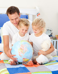 Cute siblings and their father looking at a terrestrial globe