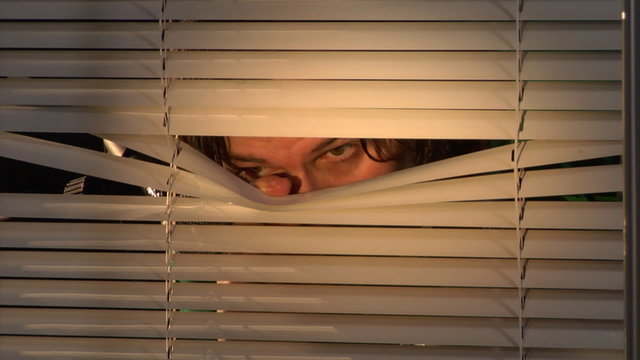 man shooting through the blinds
