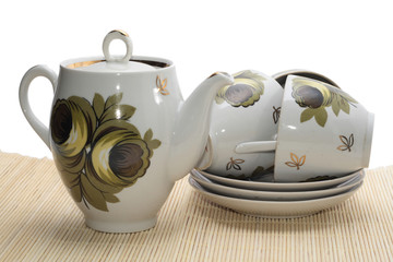 teapot with three cups on the mat.