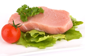 Stück rohes Fleisch mit Salat und Tomate isoliert