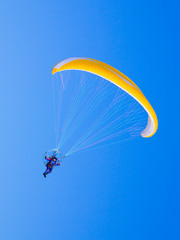 Yellow paraglider in serene cloudless blue sky