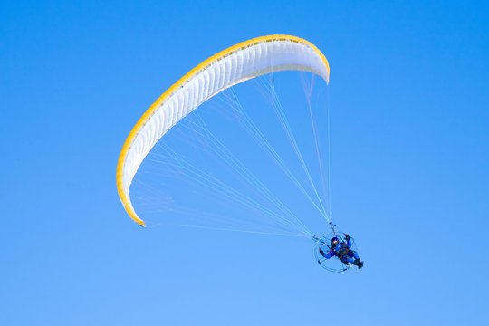 Yellow paraglider in serene cloudless blue sky
